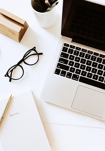 Workspace with laptop, notebook, and glasses